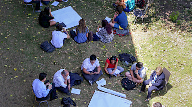 Grupos de personas sentadas en el pasto en círculo.