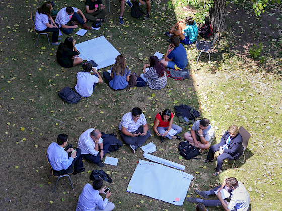 Grupos de personas sentadas en el pasto en círculo.