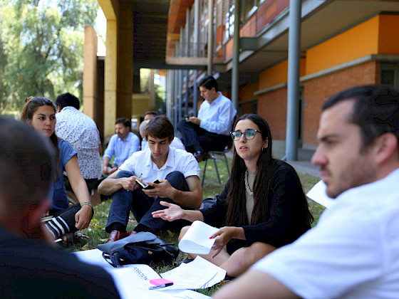 Jóvenes dialogando sentados en el pasto.
