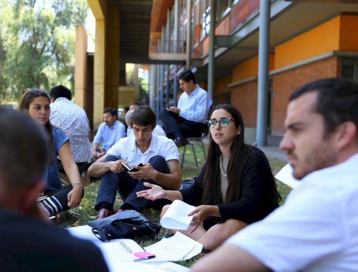 Jóvenes dialogando sentados en el pasto.