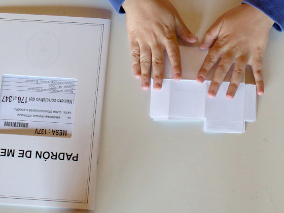 Manos doblando un voto sobre una mesa.