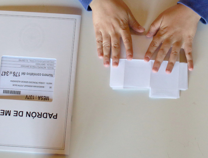 Manos doblando un voto sobre una mesa.