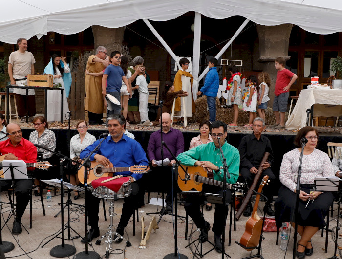 Grupo instrumental adelante y obra de teatro atrás.