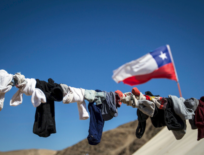 Ropa tendida contra cielo azul y bandera chilena. (Foto: Karina Fuenzalida)