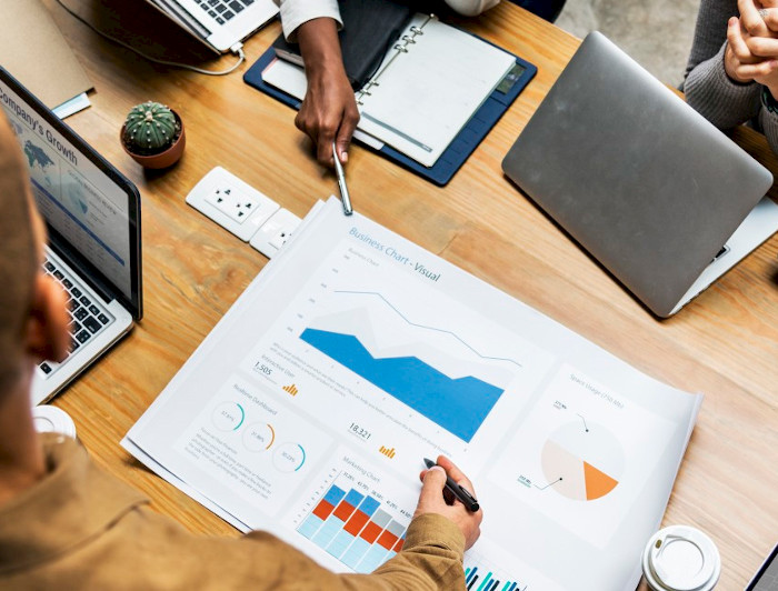 Personas sentadas en una sala de reuniones, frente a un gráfico.