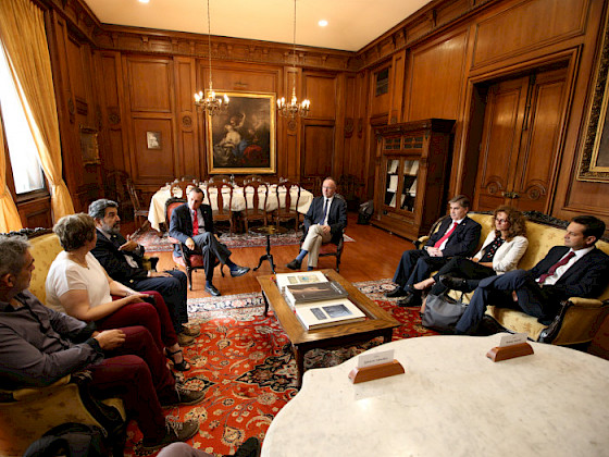 Grupo de personas sentadas, con una mesa al centro. Fotografía: César Cortés.