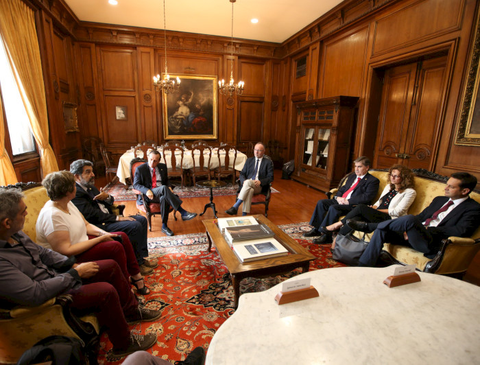 Grupo de personas sentadas, con una mesa al centro. Fotografía: César Cortés. 