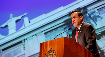 El rector Ignacio Sánchez hablando en un podio, con una imagen del Cristo de Casa Central detrás de él.