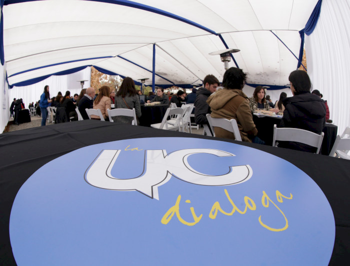 Logo de La UC Dialoga, con personas sentadas en unas mesas al fondo. 