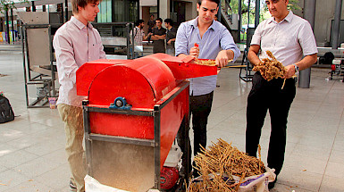 La imagen muestra dos alumnos y al decano Rodrigo Figueroa junto a una máquina trilladora