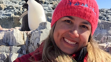 Imagen de profesora Juliana Vianna con ropa abrigada cerca de un pinguino