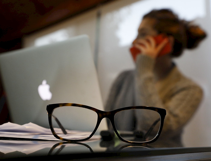 Foto de una alumna hablando por teléfono y trabajando frente a un computador.