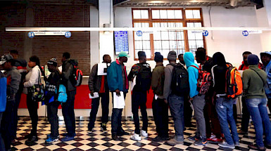 Migrantes de color en fila para obtener documentos.