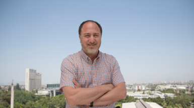 Roberto González, psicólogo UC, en la terraza del Centro de Innovación UC, y de fondo, el campus San Joaquín.
