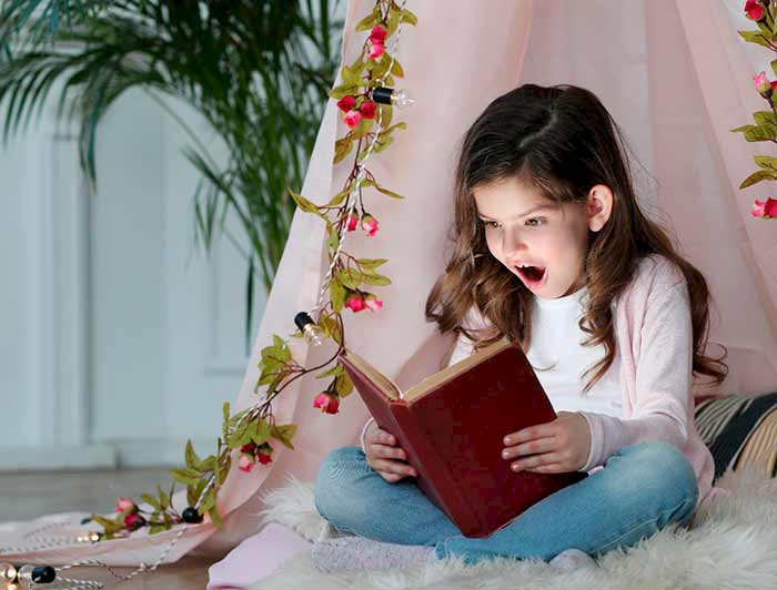 niña leyendo un libro, su rostro expresa alegría