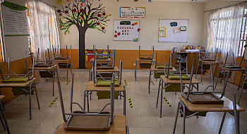 Sala de clases vacía con las sillas sobre las mesas