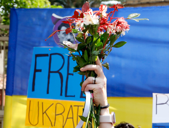 a person holding a bouquet of flowers in front of a sign that says free ukraine