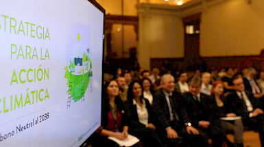 Launch ceremony of the Strategy for Climate Action in which tfuhe public and a screen with the cover of the document are visible.