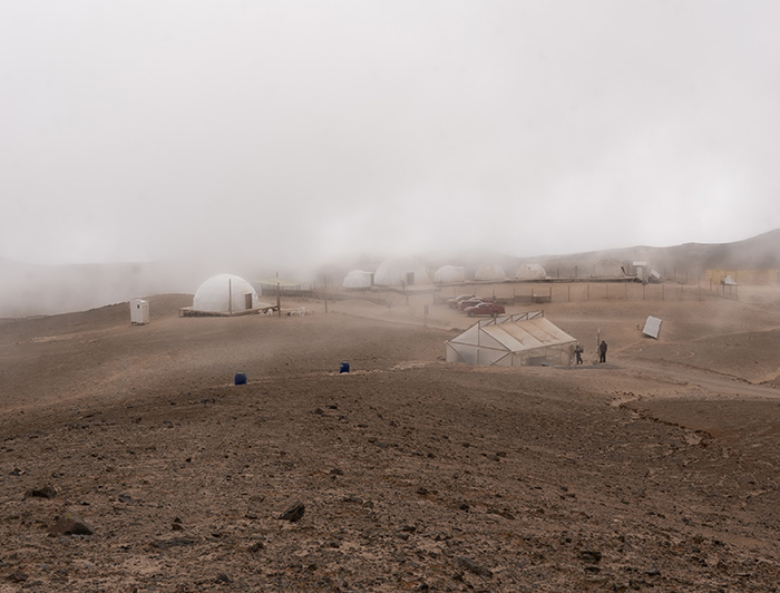 Domos e invernadero de Estación Atacama UC, entre medio de lomas de tierra y cubriéndose de niebla. 