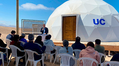 UC Chile President Ignacio Sánchez next to a white dome with the UC Chile logo and a scale model of a fog catcher.