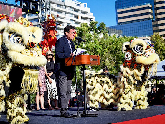 UC Chile President Ignacio Sánchez speaking on a stage next to two figures representing a lion during the celebration of the Chinese New Year.