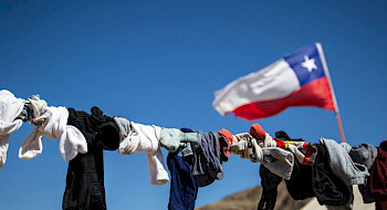 Ropa tendida contra cielo azul y bandera chilena. (Foto: Karina Fuenzalida)